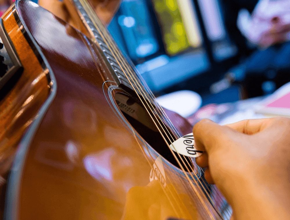A Verb guitar pick strumming an acoustic guitar